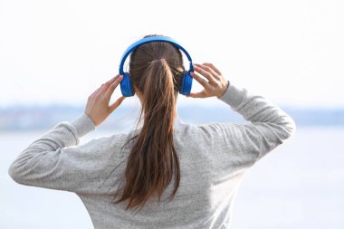 Genç kadın Nehri yakınında müzik dinlemek