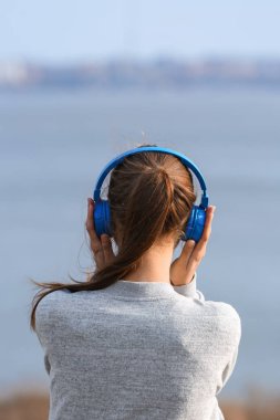 Genç kadın Nehri yakınında müzik dinlemek