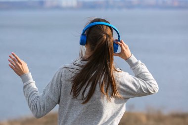 Genç kadın Nehri yakınında müzik dinlemek