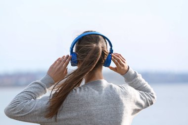 Genç kadın Nehri yakınında müzik dinlemek