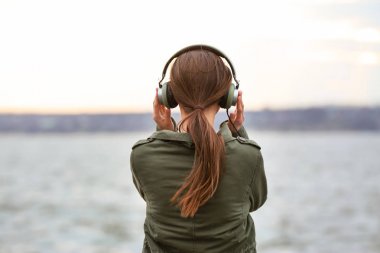 Genç kadın Nehri yakınında müzik dinlemek