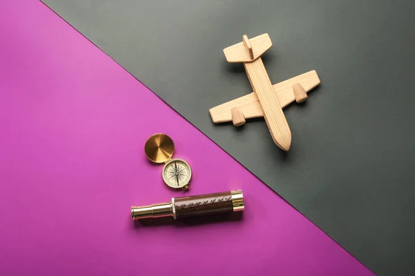 Avión de juguete con brújula y catalejo sobre fondo de color. Concepto de viaje — Foto de Stock