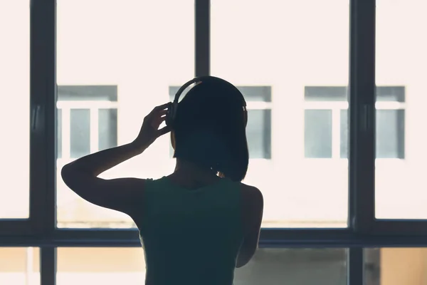 Sziluettje fiatal nő hallgat otthon zenét — Stock Fotó