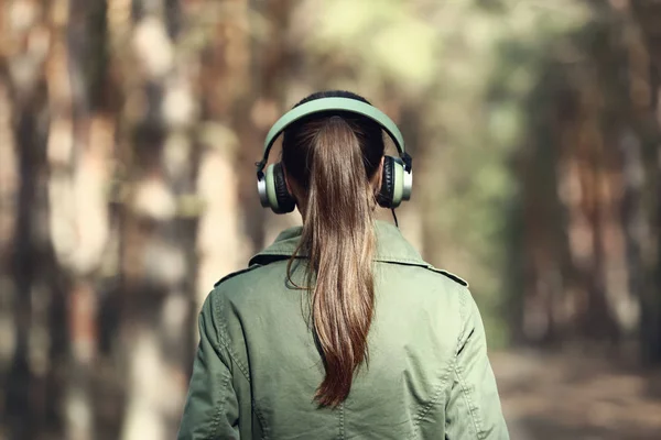 Jovem mulher ouvindo música na floresta — Fotografia de Stock