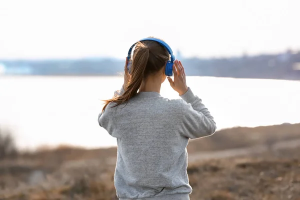 Jonge vrouw, luisteren naar muziek in de buurt van rivier — Stockfoto