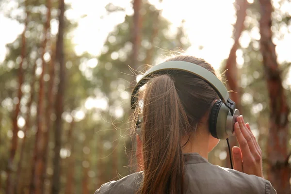 Jovem mulher ouvindo música na floresta — Fotografia de Stock