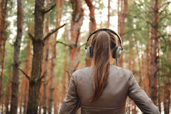 Jovem mulher ouvindo música na floresta — Fotografia de Stock