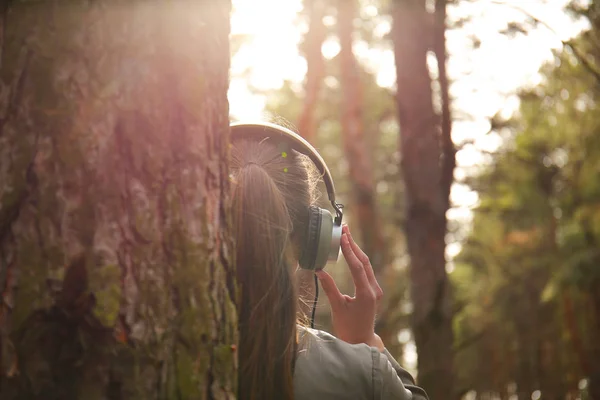 Jovem mulher ouvindo música na floresta — Fotografia de Stock