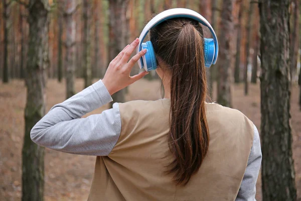 Jonge vrouw, luisteren naar muziek in bos — Stockfoto