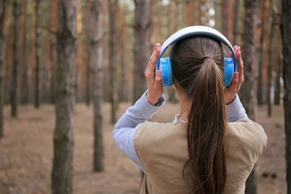 Jovem mulher ouvindo música na floresta — Fotografia de Stock