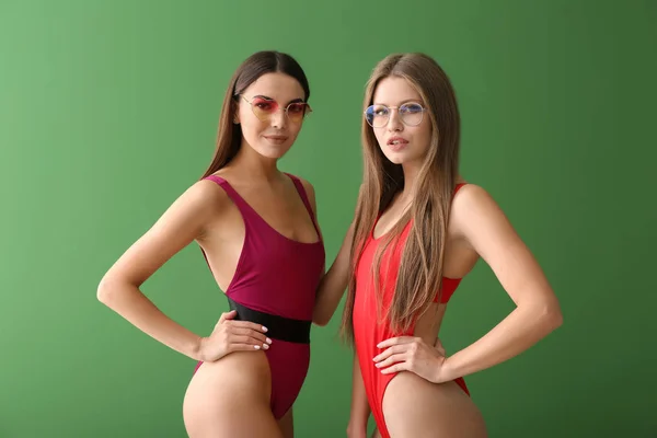 Belles jeunes femmes en maillots de bain sur fond de couleur — Photo