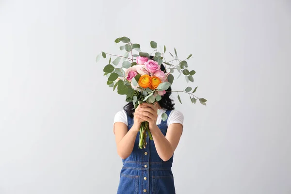 Portrait of beautiful woman with bouquet on light background — Stock Photo, Image