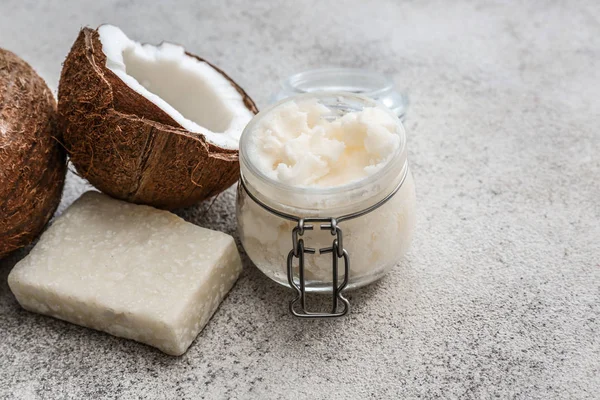 Jar of coconut oil and soap on light background — Stock Photo, Image