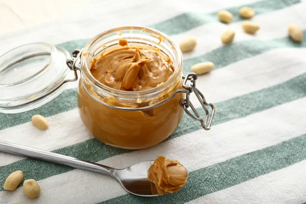 Jar with tasty peanut butter on table — Stock Photo, Image