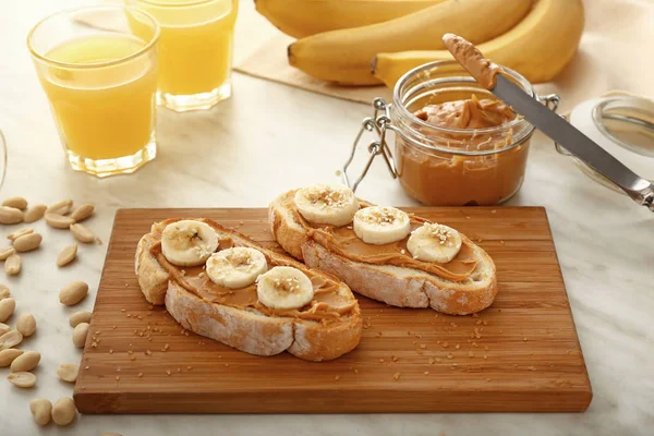 Chleb z pysznym masłem orzechowym i bananem na drewnianej płycie — Zdjęcie stockowe