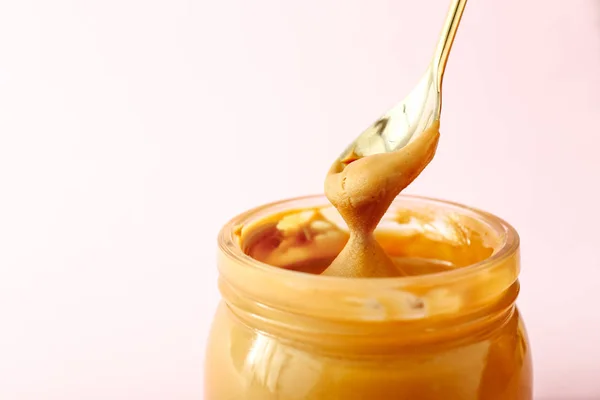 Einnahme von leckerer Erdnussbutter aus Glas auf hellem Hintergrund — Stockfoto