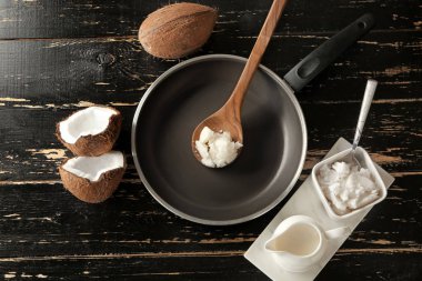 Koyu ahşap masada Hindistan cevizi yağı ile kızartma tava