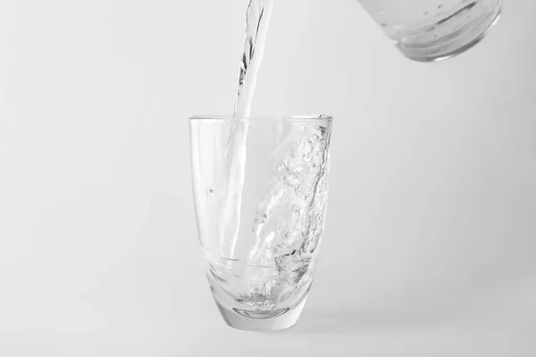 Verter agua en un vaso sobre un fondo claro —  Fotos de Stock