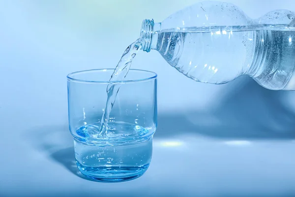 Pouring of water into glass on color background — Stock Photo, Image