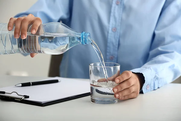 Woman pouring water into glass on table — Stock Photo, Image