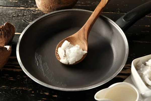 Padella con olio di cocco sul tavolo di legno scuro — Foto Stock
