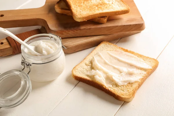 Aceite de coco con sabroso pan tostado sobre mesa blanca — Foto de Stock