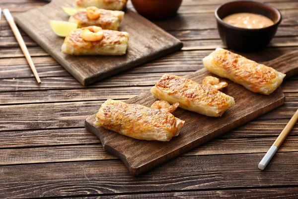 Board with tasty fried spring rolls on wooden table — Stock Photo, Image