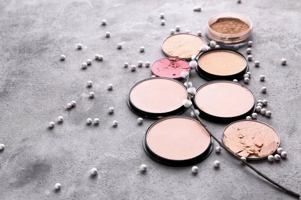 Different facial powder and blusher on grey background