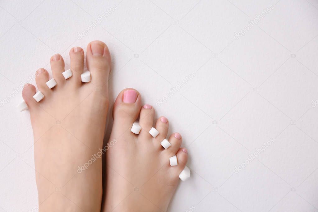 Woman with toe separators and fresh pedicure on light background