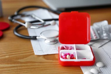 Klinikte masa üzerinde stetoskop, kardiyogram ve haplar