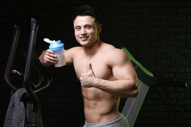 Karanlık arka planda protein sallama ile sportif adam