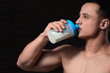 Karanlık arka planda sportif adam içme protein shake