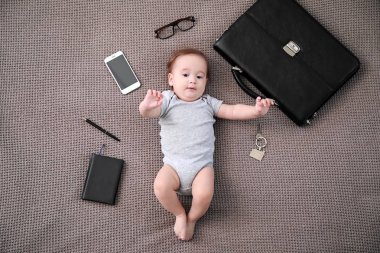 Evrak çantası, anahtarlar, cep telefonu ve Kırtasiye ile sevimli bebek çocuk yumuşak ekose üzerinde yatıyor