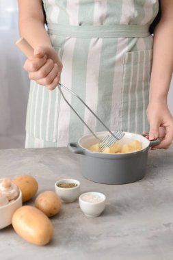 Woman preparing tasty mashed potato at table clipart