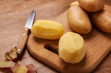 Ahşap masada çiğ patates ve bıçak ile kesme tahtası