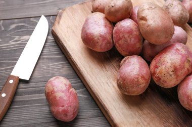 Ahşap masada çiğ patates ve bıçak ile kesme tahtası