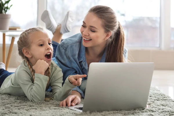 Молодая мать с маленькой дочкой смотрят мультфильмы дома — стоковое фото