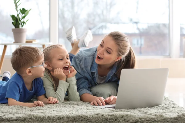Молодая мама с маленькими детьми смотрит мультики дома — стоковое фото