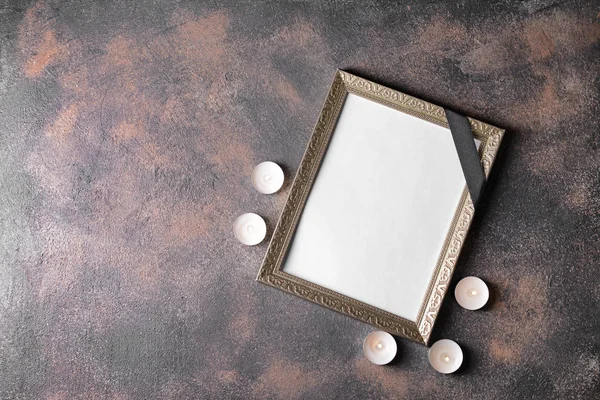 Blank funeral frame and candles on grunge table