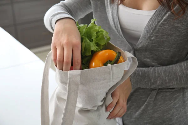 エコバッグを屋内で新鮮な野菜を持つ若い女性 — ストック写真