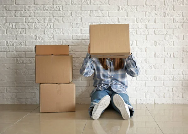 Nő a mozgó dobozok közelében téglafal a szobában — Stock Fotó