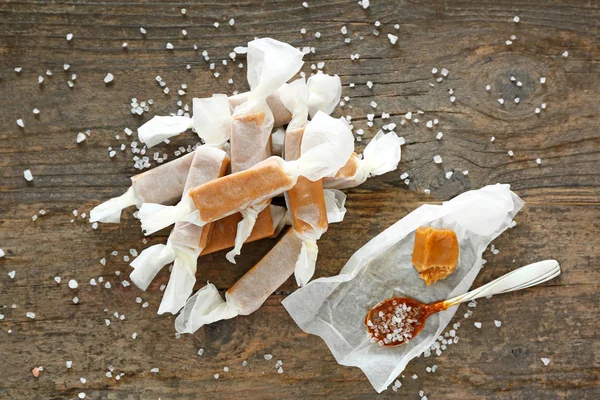 Tasty salty caramel candies on wooden table — Stock Photo, Image