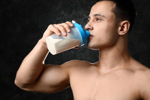 Sportig man dricker protein skaka på mörk bakgrund — Stockfoto
