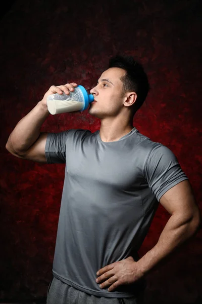 Sporty man drinking protein shake on dark background — Stock Photo, Image