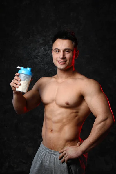 Sportlicher Mann mit Proteinshake auf dunklem Hintergrund — Stockfoto