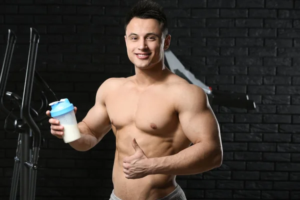 Sporty man with protein shake on dark background