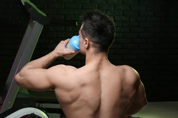 Sporty man drinking protein shake on dark background — Stock Photo, Image