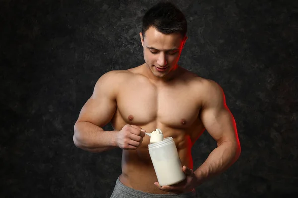 Sporty man with protein on dark background — Stock Photo, Image