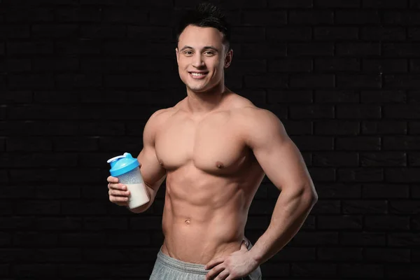 Sporty man with protein shake on dark background