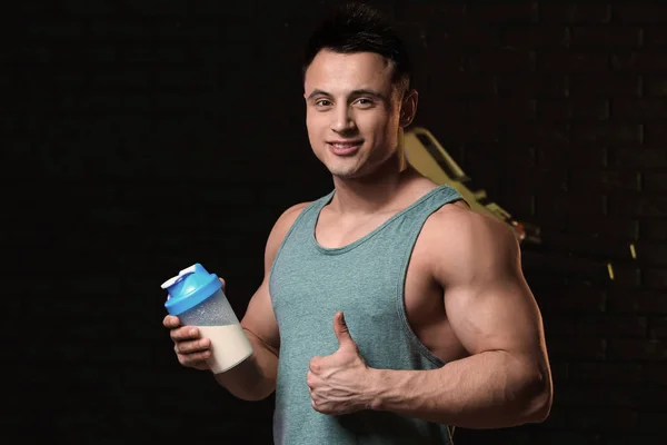 Karanlık arka planda protein sallama ile sportif adam — Stok fotoğraf